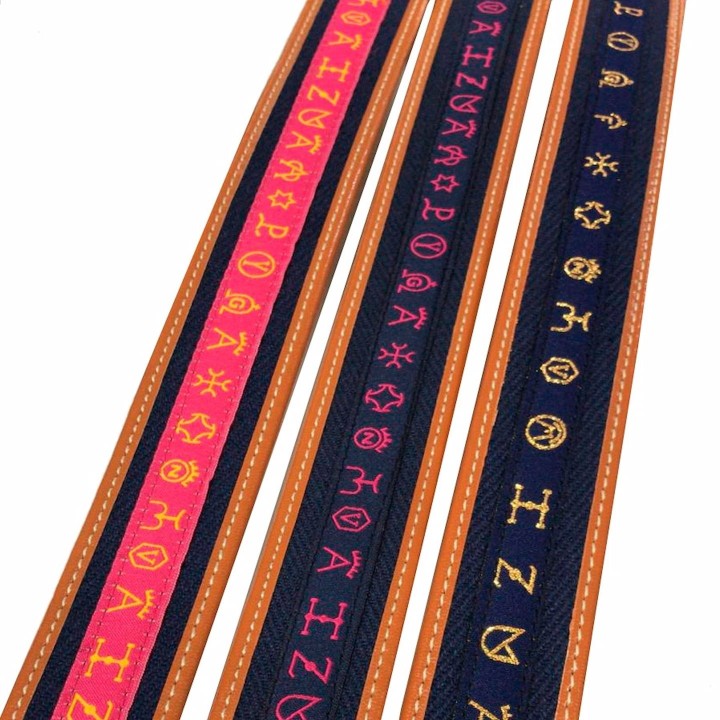 Spanish leather bullfighting belt with gold-embroidered cattle ranch brands on pink and navy ribbon.