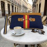 Cartera de mano con bandera de España y estribo, color azul, en una terraza de Madrid