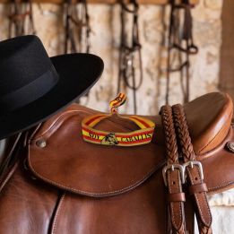 Bracelet Soy Caballista sur une selle à côté d’un chapeau cordouan