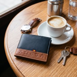 Cartera de piel azul con hierros ganaderos en una mesa de bar con café