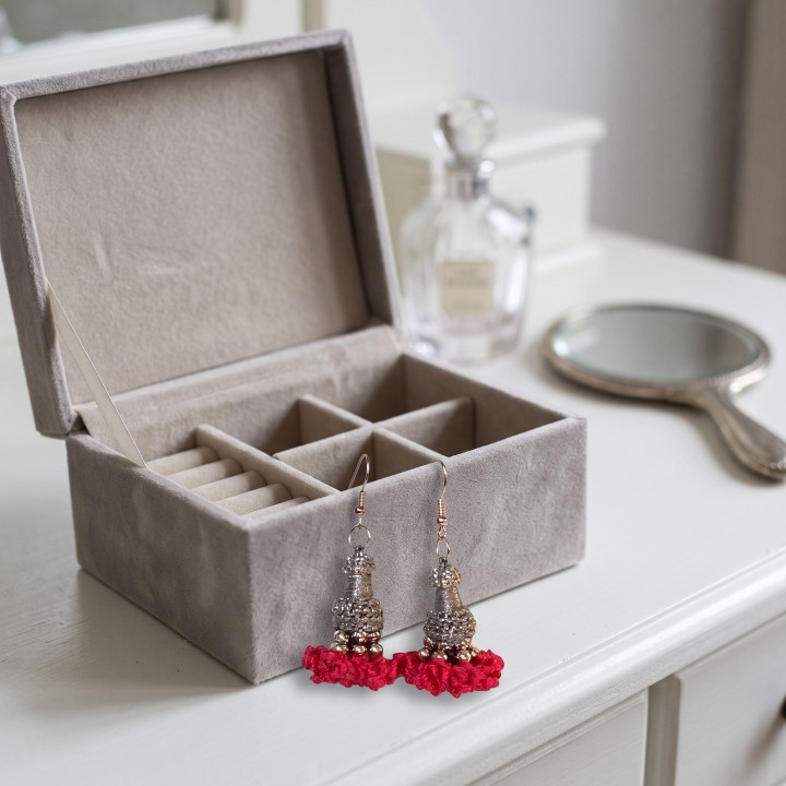 Bullfighter tassel earrings next to a jewellery box on a dressing table