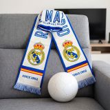 Official Real Madrid scarf on a sofa next to a football