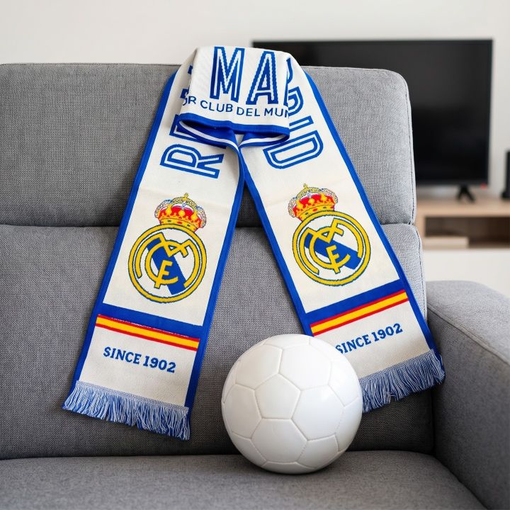 Official Real Madrid scarf on a sofa next to a football