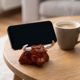 Ceramic bull head phone stand holding a phone on a side table