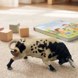 Taureau jouet qui charge sur un tapis d’enfant avec des cubes en bois