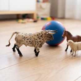 Taureau de combat jouet au trot sur le sol d’une chambre d’enfant