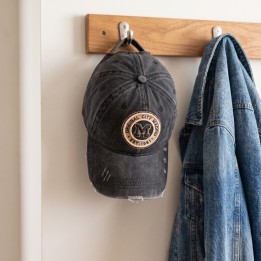 Gorra Madrid de tela desgastada colgada en un perchero junto a una chaqueta vaquera
