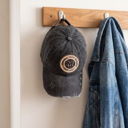 Distressed Madrid cap hanging on a coat rack next to a denim jacket