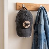 Distressed Madrid cap hanging on a coat rack next to a denim jacket