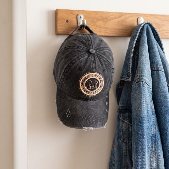 Distressed Madrid cap hanging on a coat rack next to a denim jacket