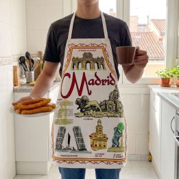 Young man wearing the Madrid souvenir apron with churros and chocolate in a kitchen overlooking Madrid rooftops