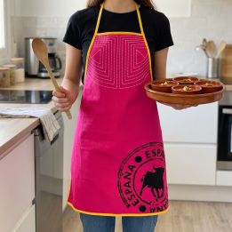 Femme en cuisine avec le tablier Capote fuchsia, une cuillère en bois et des bols de gaspacho