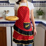 Chica en una cocina andaluza con el delantal de flamenca rojo de lunares y un plato de tortilla de patatas